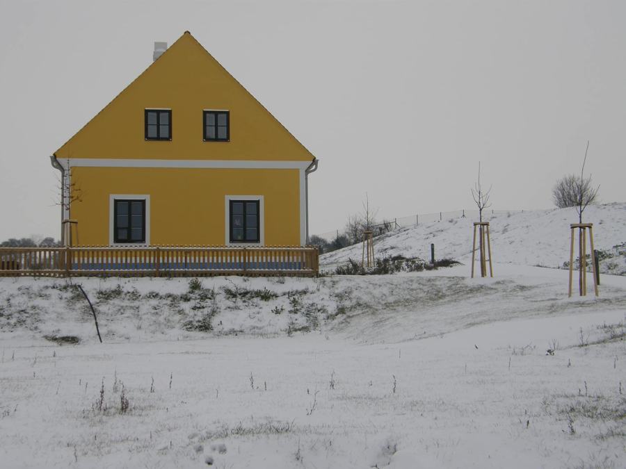 Žlutý štít chalupy nad zasněženou zahradou
